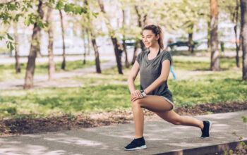 smiling young sportswoman looking away while working out in sunny park