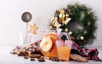 Home made apple punch served with Christmas cookies, spices, decorated with napkin over the grey background