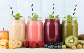 Smoothies, fruits and berries on blue wooden background